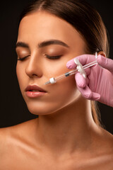 Obraz premium Cosmetologist does injections for lips augmentation and anti wrinkle in the nasolabial folds of a beautiful woman. Women's cosmetology in the beauty salon.