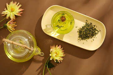 Tea concept with white tea set of transparent cup and teapot decorated with fresh flowers on the brown background. Mid Autumn Festival minimalist design