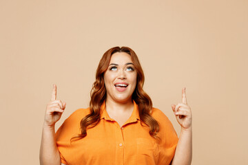 Young happy ginger chubby overweight woman wear orange shirt casual clothes point index finger...