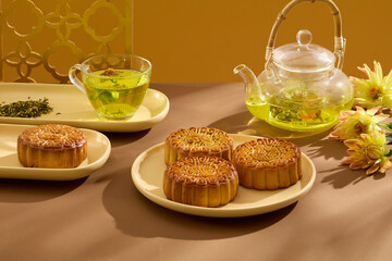 Traditional food and drink tea concept. Baked mooncakes displayed with a set of warm tea on brown plate. Mid-autumn festival food moon cake. Food advertising