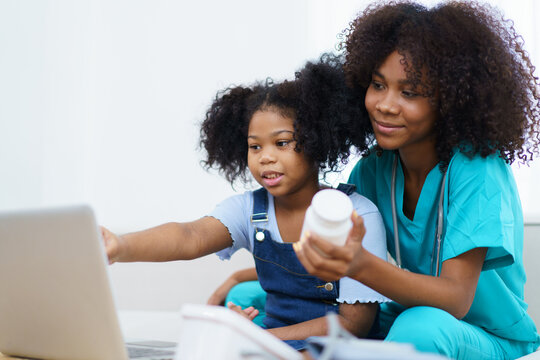 American - African Ethnicity Girl Sitting And Talking With Doctor And Doctor Explain About Treatment And Medicine To The Girl, A Professional Pediatrics Kindly Explains Or Talks With Little Girl.