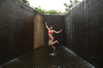 Pretty Asian female in a swimsuit is jumping happily and relaxing at the spillway.