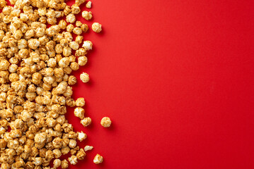 Overhead shot of a pile of delectable popcorn against red background, with space for your message or promotion