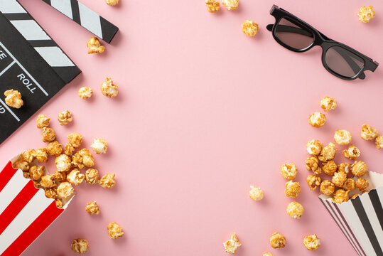 Movie Time Essentials: Overhead view of cheese and caramel popcorn, 3D glasses, and a clapperboard on a pastel pink background, perfect for gathering with friends to watch a film