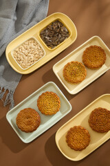 Some ceramic dishes in pastel color are featured mooncakes and pumpkin seeds with sunflower seeds. A scarf is decorated. Mid-autumn festival poster for product demonstration