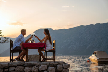Couple in love drinking wine on romantic dinner at sunset on the beach. People love travel concept