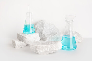 Cosmetics presentation with stone pedestal and blue liquid in flask