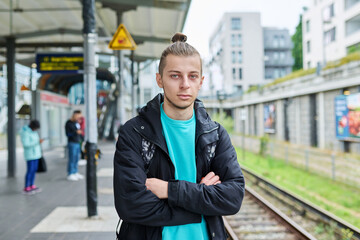 Fototapeta premium Portrait of young confident guy at railway station of electric city train