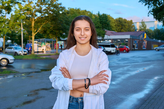 Portrait of teenage girl with crossed arms on town street in sunset light