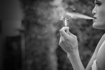 Black and white close up of Asian transwoman or transgender holding cigarette and smoking in...