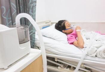 Ill young Asian girl sleeping on bed in hospital. Sick kid with Medical ultrasonic inhaler, nebulizer, nebular with mask. Respiratory medicine. Asthma breathing treatment. Asthmatic health equipment. - obrazy, fototapety, plakaty