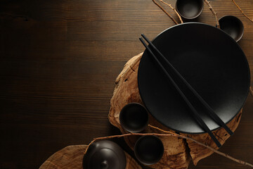 Empty, black Chinese dishes with chopsticks on a dark background