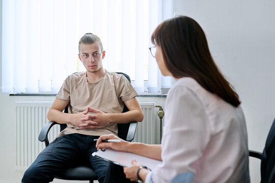 Young male student at therapy meeting with college psychologist counselor