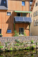 Wohnhaus mit Holzfassade am Wasser mit Balkonkraftwerk - obrazy, fototapety, plakaty