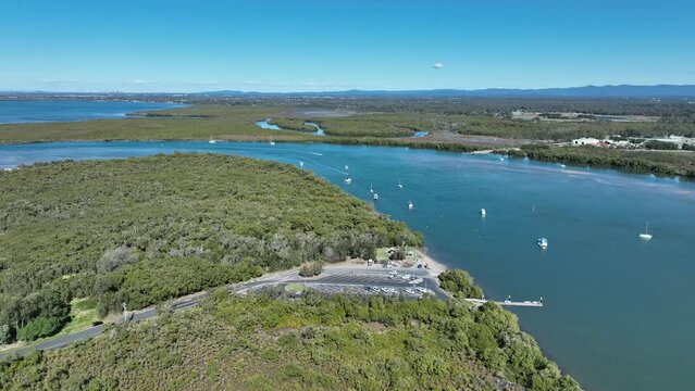 Aerial drone shot orbiting Beachmere Boat Ramps on Caboolture River, Boats in river opening to the Ocean Moreton Bay. Brisbane City in background Queensland.