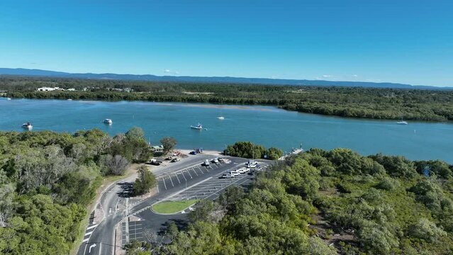 Aerial drone shot orbiting Beachmere Boat Ramps on Caboolture River, Boats in river opening to the Ocean Moreton Bay. Brisbane City in background Queensland.
