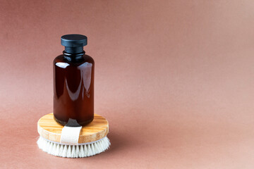 Shower gel or liquid soap and wooden brush on beige background.Copy space