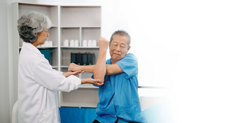 Obraz premium Asian physiotherapist helping elderly man patient stretching arm during exercise correct with dumbbell in hand during training hand in bed in clinic