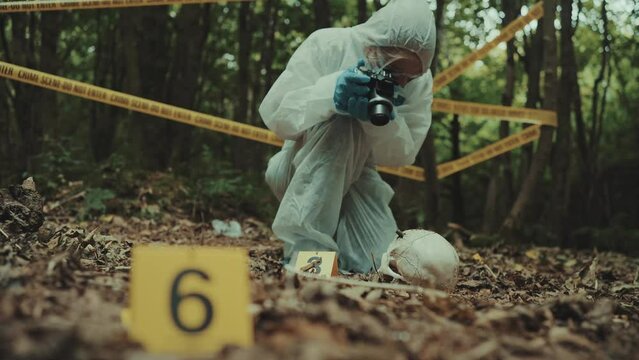 Woman forensic police investigator taking pictures of evidences on a crime scene