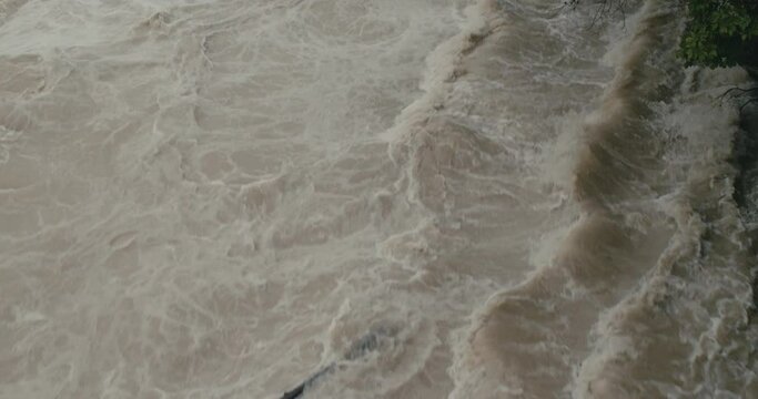River floods shore overflow high water debris top down in slow motion
