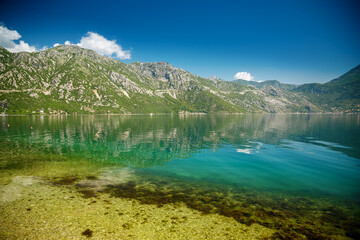 Fototapeta na wymiar View of famous Bay of Kotor with transparent blue sea and mountains on a beautiful sunny day