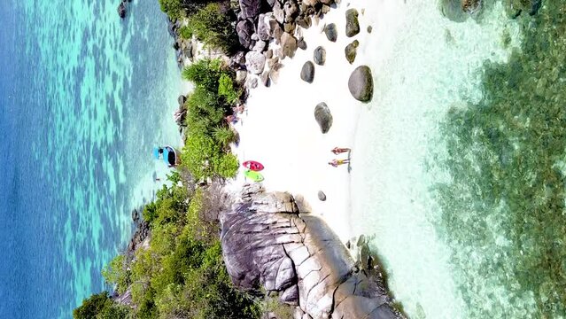 A couple on the beach of Kla Island in front of Koh Lipe Island Southern Thailand, turqouse colored ocean and white sandy beach with a kayak at Ko Lipe on a sunny day