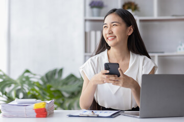 Young asian business woman using laptop and using phone note, woman officer hard working...