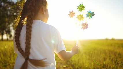 baby pinwheel. little girl silhouette plays with windmill a toy wind in the park. happy family...