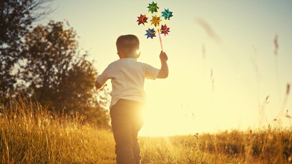 baby pinwheel. little boy silhouette plays with windmill a toy wind in the park. happy family...