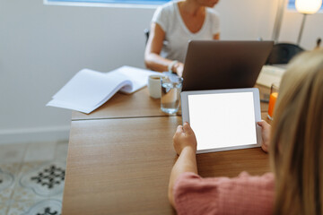 Little girl playing games on a tablet while her mother works