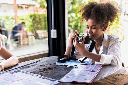 Black tourist woman using camera taking pictures in cafe