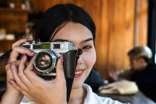 Portrair young woman using vintage camera taking pictures