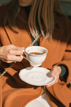 Close-up of a stylish woman sitting at a cafe drinking a cup of coffee