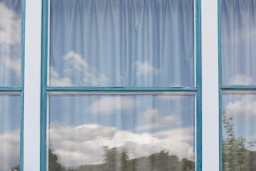 Window with blue frame and closed gray curtain. Window detail. Fenster mit blauem Rahmen und geschlossenem grauen Vorhang. Fenster Detail. 