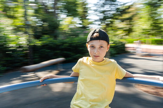Boy spinning around on a carousel in a park in summer, Georgia