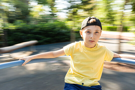 Boy spinning around on a carousel in a park in summer, Georgia