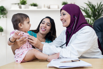 Indian mother with little baby visit female muslim general pediatrician wear hijab in clinic for check-up, Healthcare and medical, Multi ethnic, diversity, occupation. middle eastern.