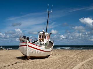 Beached fishing boat on a sandy beach with the blue sea in the background