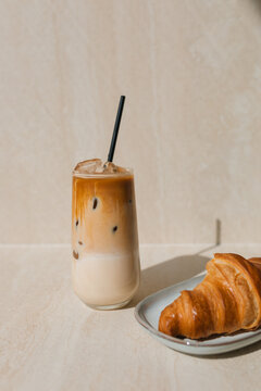 Close-up of a glass of iced coffee and a croissant on a table