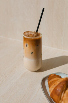 Close-up of a glass of iced coffee and a croissant on a table