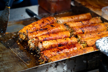 Grilling barbecue meatloaf rolled with vegetables at traditional night market in South Korea.