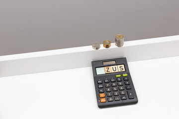 Coins in a post and next to it a calculator with the word zusame. The concept of pension contributions for the future and old age. The concept of raising premiums for entrepreneurs