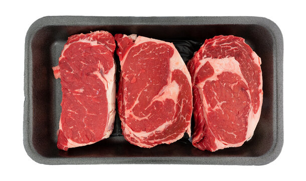 Top view of three ribeye steaks in a black foam retail meat tray isolated on a white background.