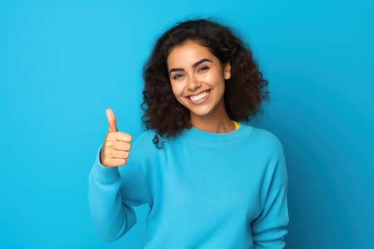 Happy businesswoman showing thumb up over blue background. Wearing a shirt and Looking at the camera.