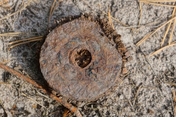 one rusty brown iron old disk lies on the gray sand on the street