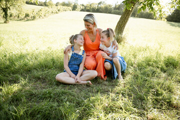 Naklejka na ściany i meble beautiful woman , mother with orange dress with her two daughters outdoor in the nature