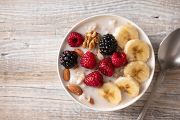 Oatmeal with fresh berries, nuts, and banana fruit. Healthy food concept. Top view.

