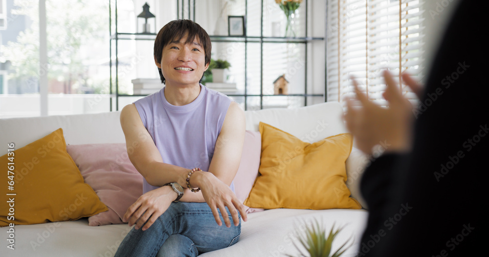 Wall mural Gay queer asian man non-binary influencer sitting easy at home sofa. Asia non binary LGBT young guy adult two people happy relax smile talking asking advice face to face in mental health care therapy.