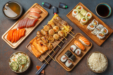 Assortiment des plats japonais: sushi, maki, california rolls, brochettess, soupe miso, salade de choux, poke bowl sur des ardoises et fond noir. Ensemble de cuisine japonaise.