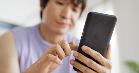 Adult people asia single LGBT gay man sitting at home sofa looking at dating game tinder app on mobile phone. Relax smile choose lover enjoy playing right swipe to find love couple match flirt chat.